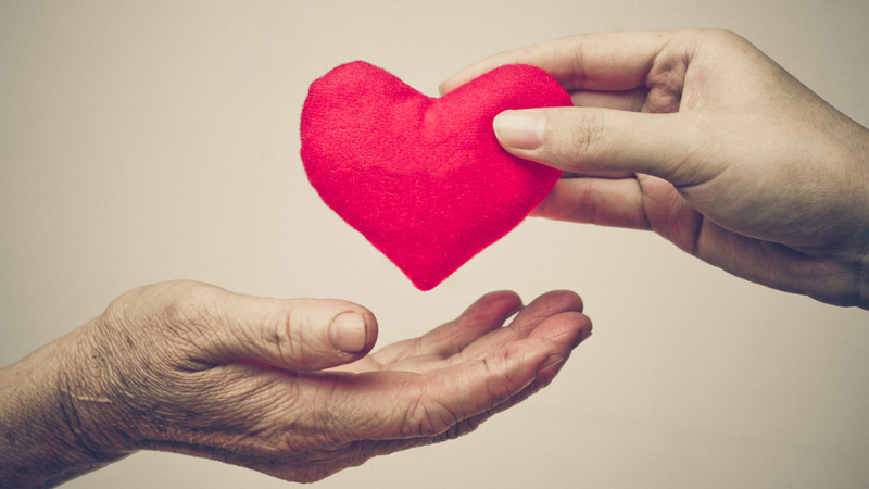 Hands passing a red heart